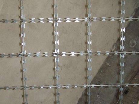 O bucată de plasă de sârmă sudată din oțel inoxidabil cu deschidere pătrată pe fundal gri.